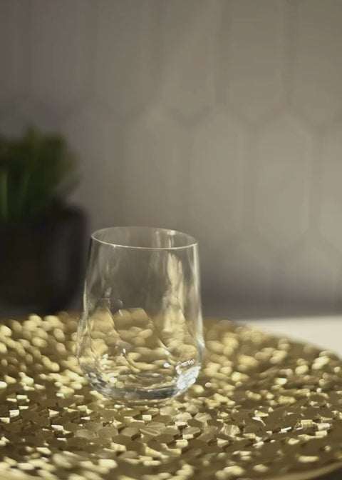 Pour of MALVAC Premium Sorrel Brew in a glass filled with ice, the glass is placed on a gold tray, and the video has a natural background. The video concludes with still images of a bottle of MALVAC Premium Sorrel Brew Low Sugar Blend. There is no sound and the video loops. 